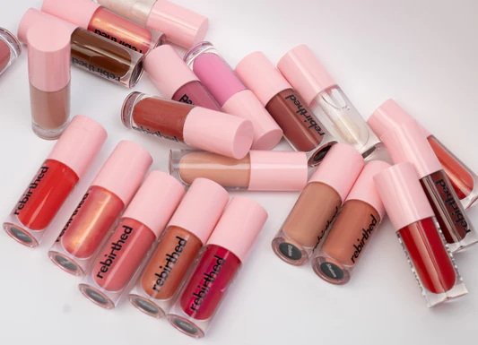 A selection of Rebirthed Makeup lip colours arranged against a soft pink background